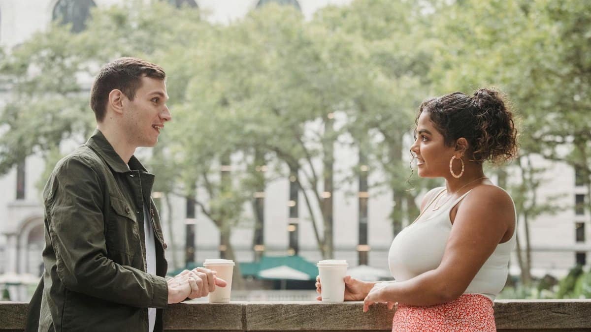 Two young adults engaging in a friendly coffee break conversation outdoors, capturing lifestyle and relationships.