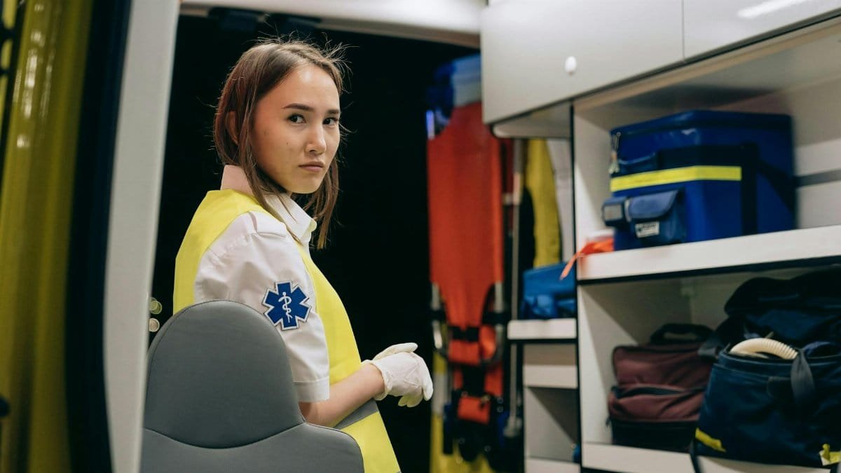Young female paramedic inside an ambulance wearing a reflective vest at night.
