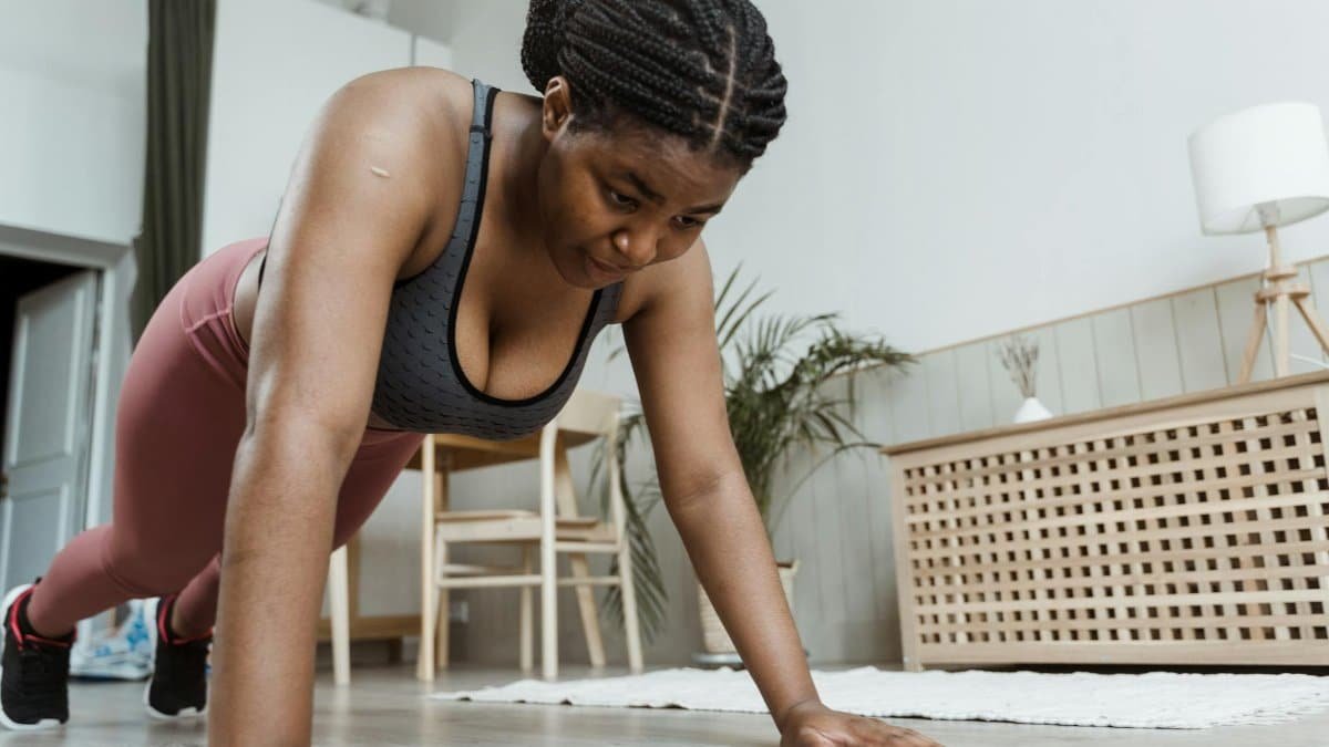 Plus-size woman performing push-ups indoors, emphasizing fitness and healthy living.