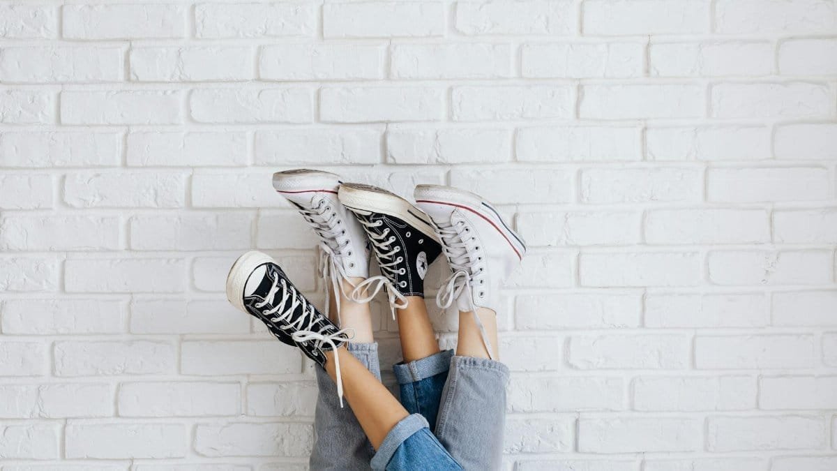 Fashion-forward sneakers displayed upside down against a white brick wall for stylish urban appeal.