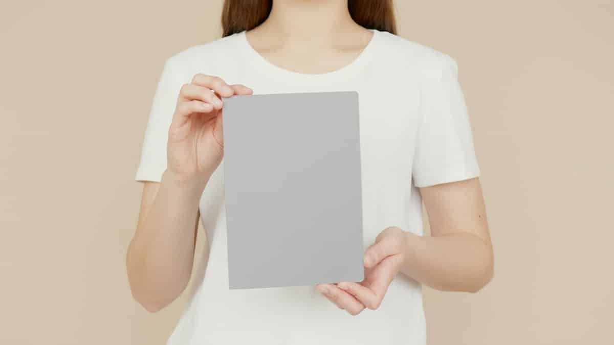 Close-up of a woman in a white shirt holding a blank notepad with copy space.