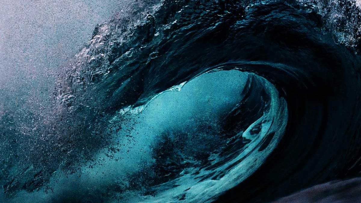 Dramatic capture of a powerful ocean wave with dark blue tones.