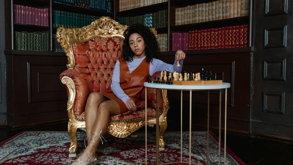 Elegant woman in a vintage armchair playing chess in a classic library. A moment of strategy and reflection.