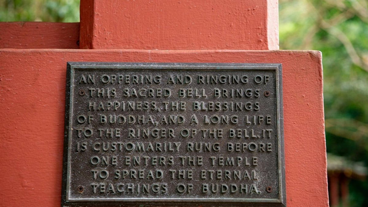 Close-up of a Buddhist plaque with teachings on a vibrant red wall.
