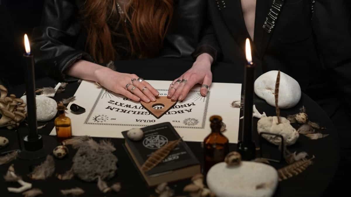 A mysterious scene with people using a Ouija board surrounded by candles and mystical items.