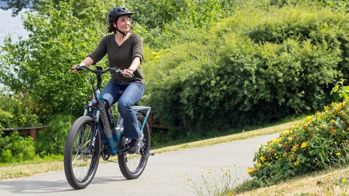 Woman biking on a scenic path in Seattle, showcasing modern electric bike and lifestyle.