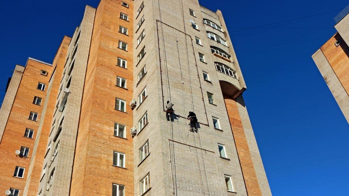 Tall high-rise building with workers performing maintenance on the facade.