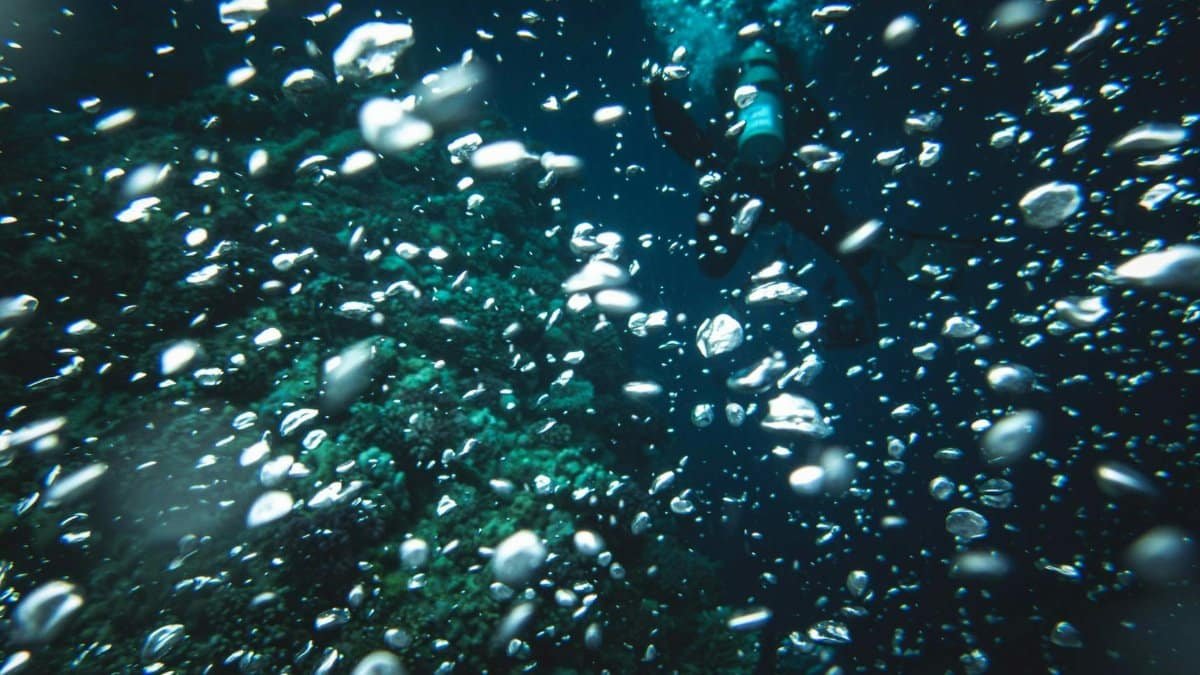 Scuba diver submerged, surrounded by air bubbles underwater, exploring ocean depths.