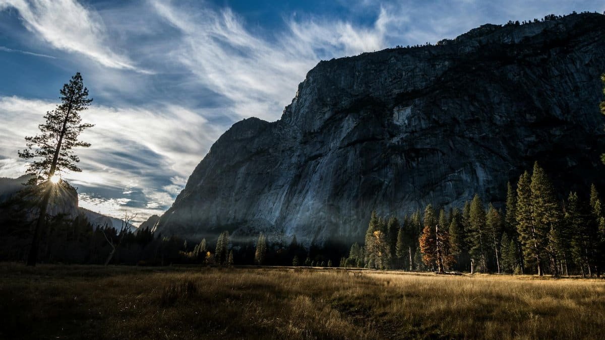 Captivating view of Yosemite Valley cliffs and trees at sunset under a dramatic sky.