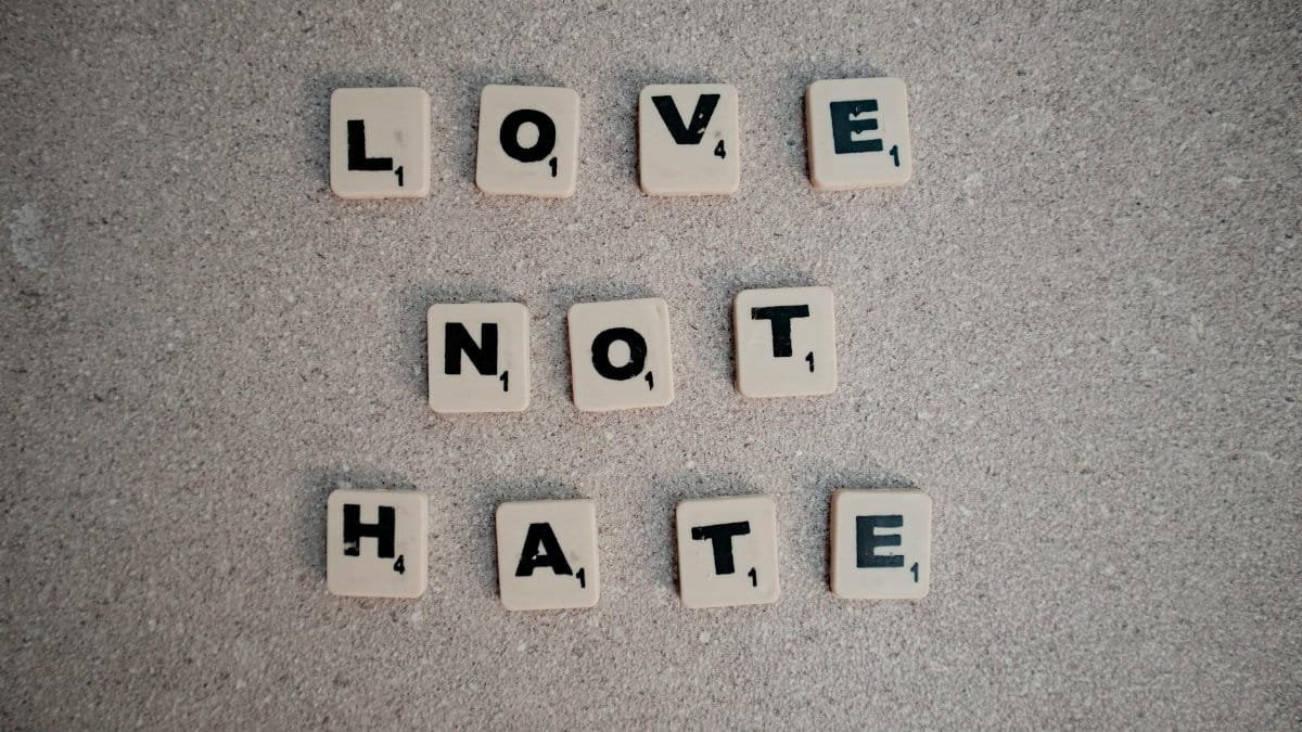 Scrabble tiles on pavement spelling the inspirational message 'Love Not Hate'.