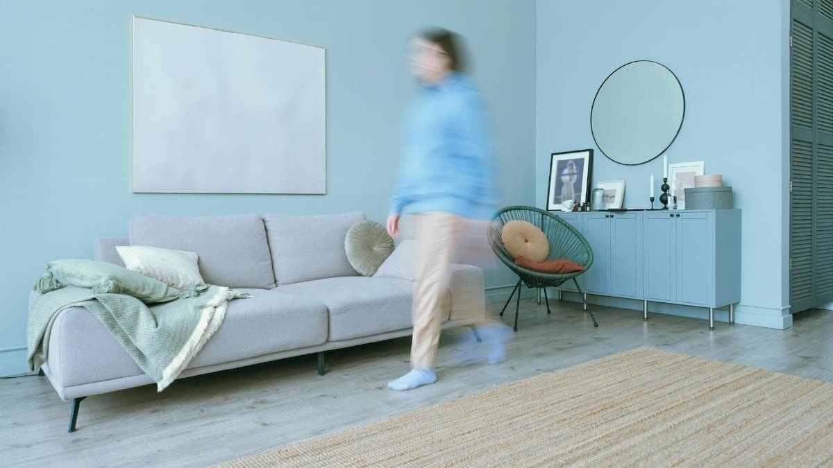 Blurred figure moves in a stylish, minimalist living room with blue accents.