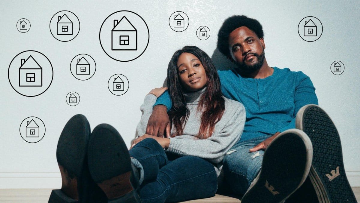Couple sitting on the floor dreaming about new home ownership surrounded by house icons.