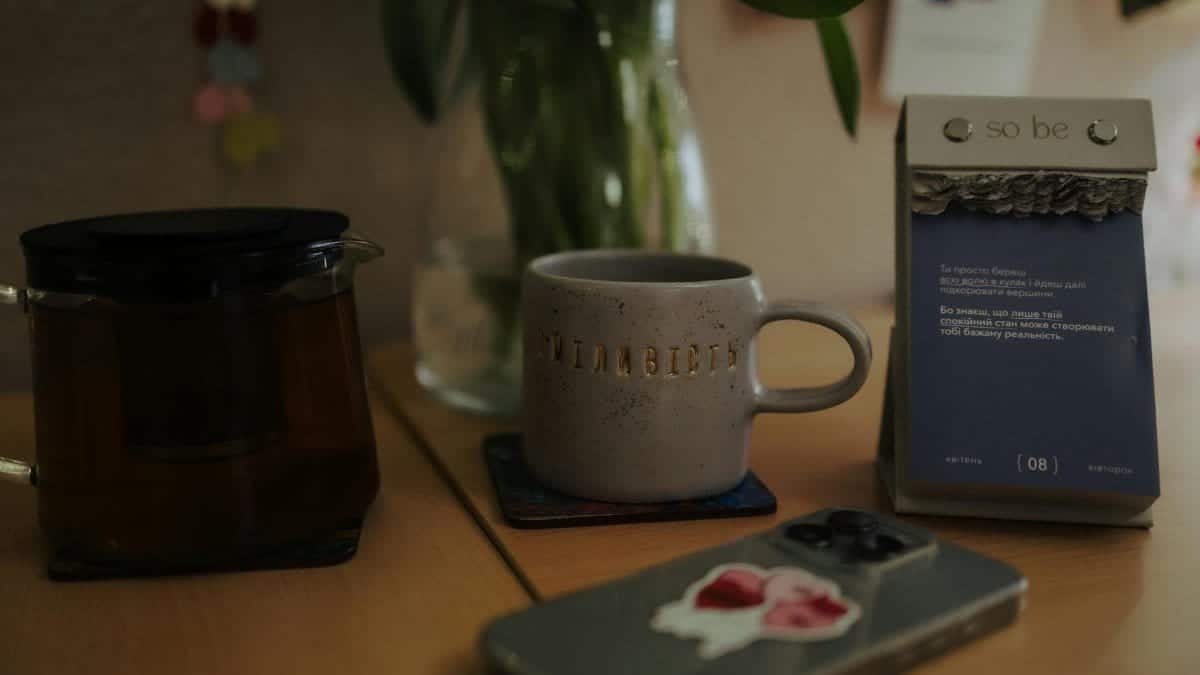 A warm, inviting setup with a tea pot, mug, and calendar on a wooden desk.
