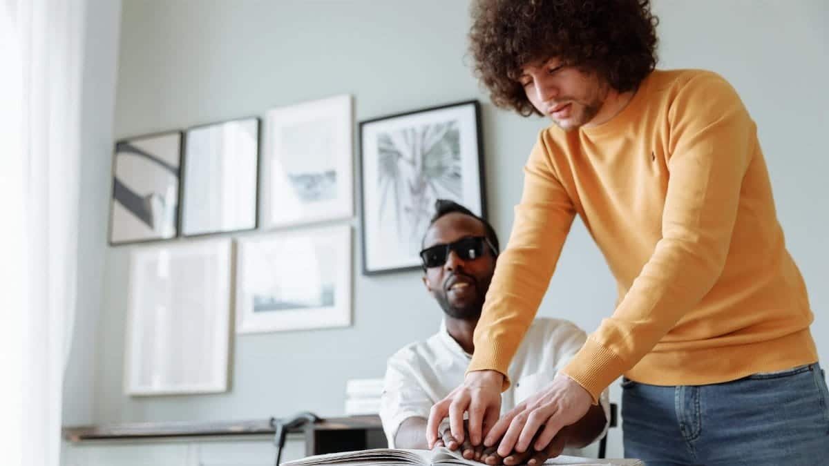 Two men engaged in Braille reading, promoting assistive technology and independence.