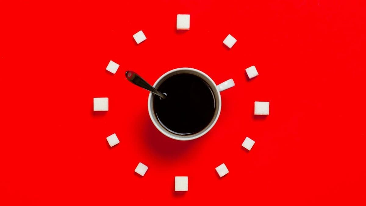 Artistic coffee composition with sugar cubes on a striking red background, from above.