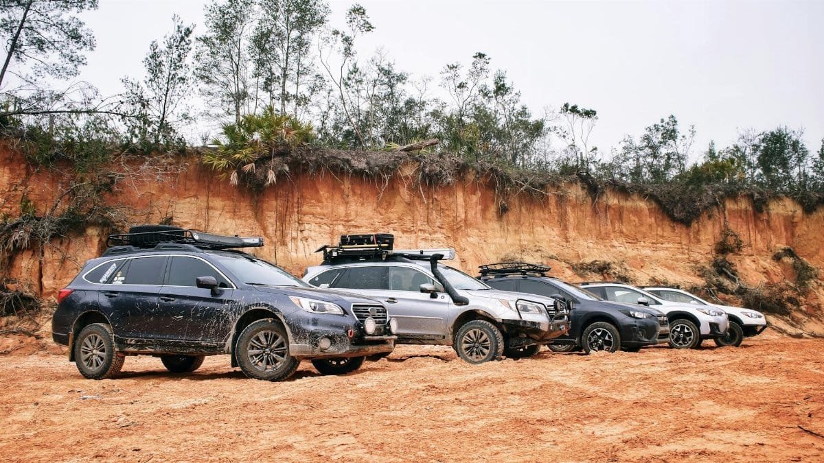 A lineup of SUVs parked on a dirt road beside a rugged terrain, ready for an off-road adventure.