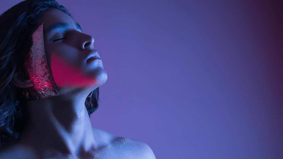 Side profile portrait with neon lighting, capturing vibrant artistic expression under a colorful backdrop.