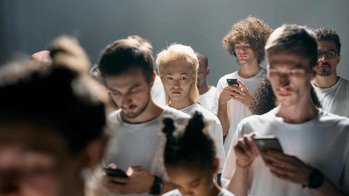 A diverse group of people looking at smartphones, illustrating social isolation in modern technology.