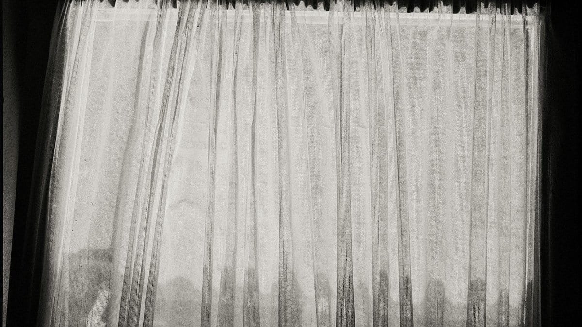 Black and white photo of sheer curtains with a sense of mystery and subtle lighting.