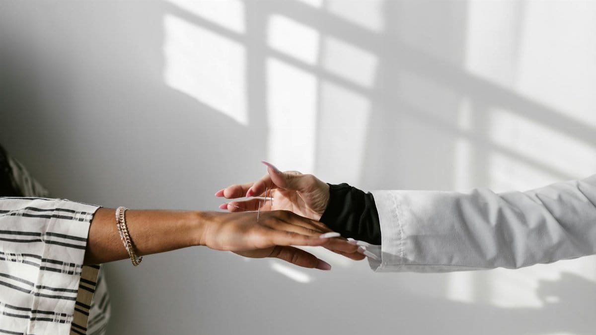 A healing acupuncture session showing careful needle application to the hand for wellness.