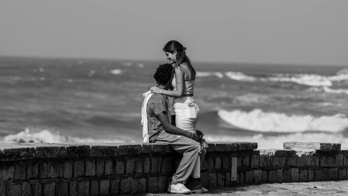 Black and white photo capturing a couple's tender moment by the ocean in Mar del Plata.
