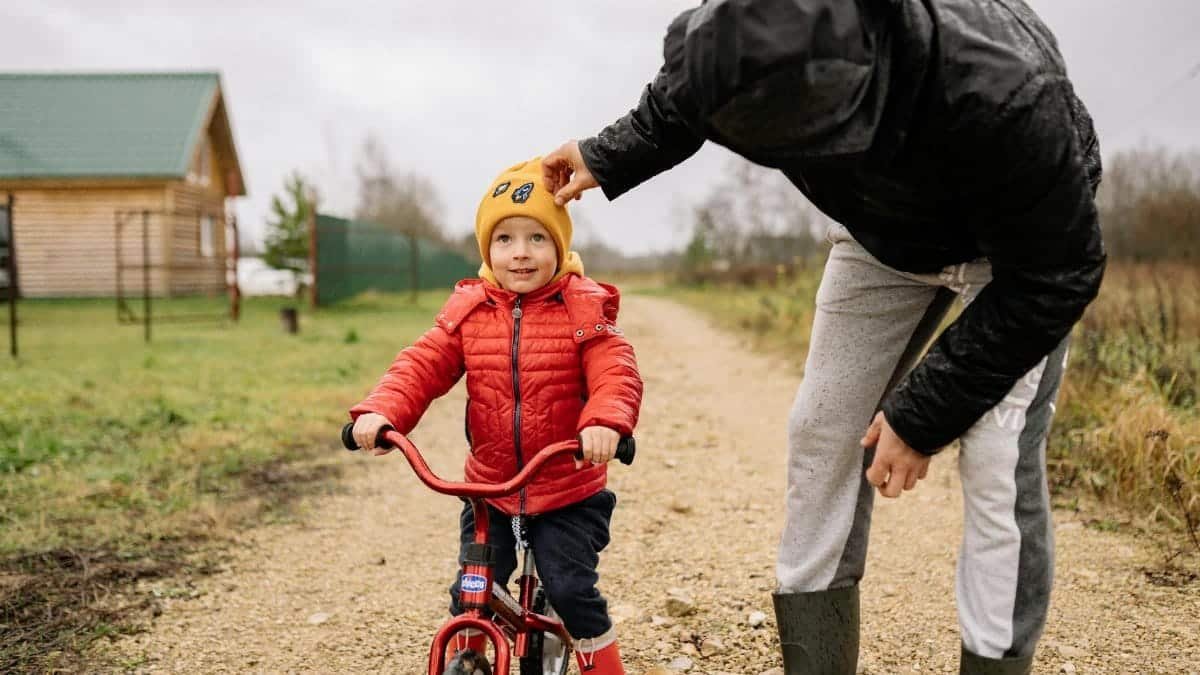 A father and child enjoy quality time biking outdoors on a countryside path in autumn.