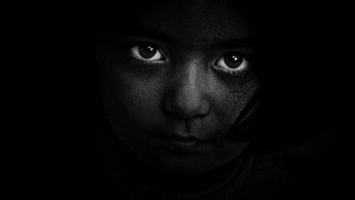 Intense black and white portrait of a child with captivating eyes, evoking mystery and emotion.