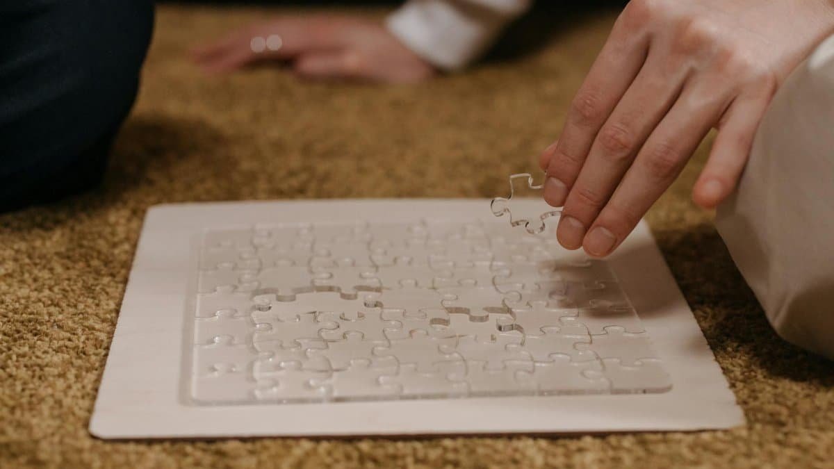 Hand placing piece in transparent puzzle, symbolizing leisure and problem-solving.