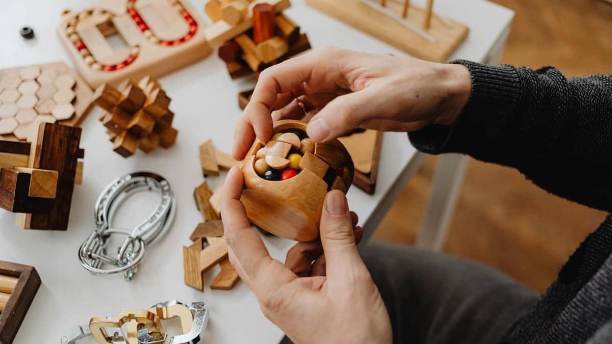 Person solving wooden puzzles with various toy designs. Perfect for mind games enthusiasts.