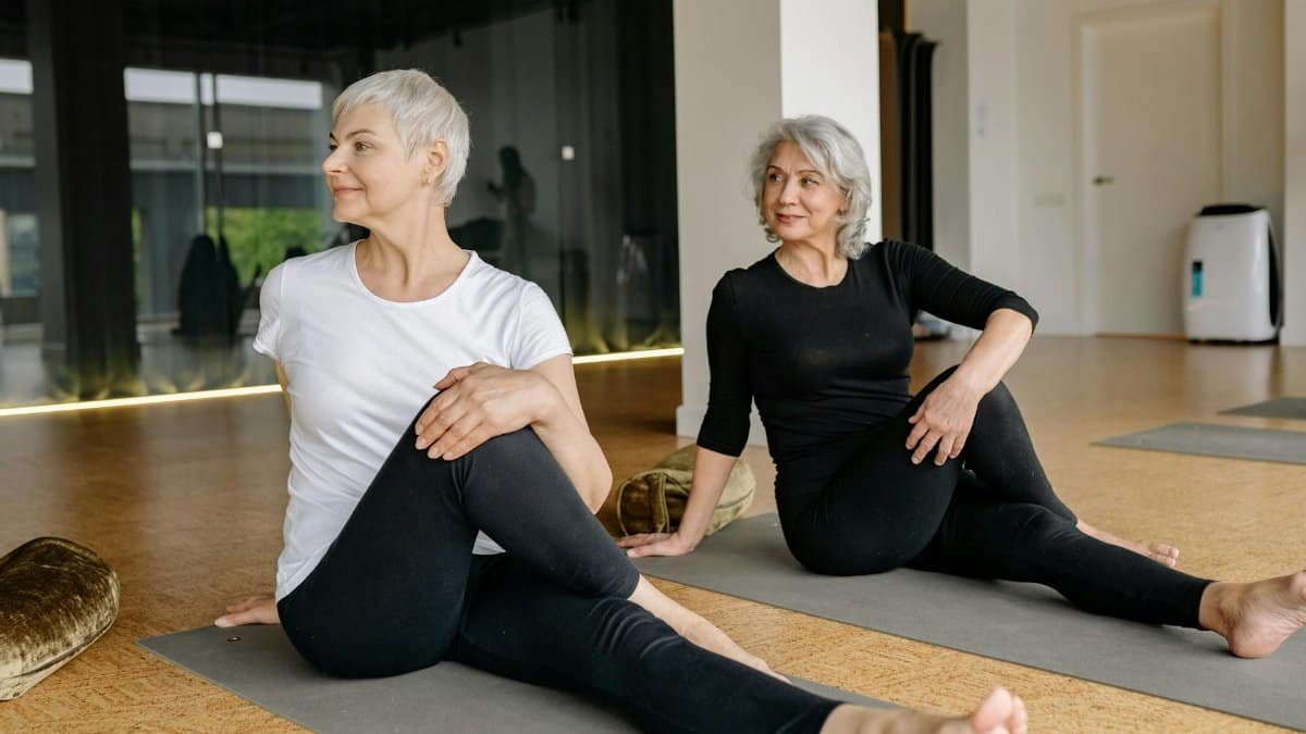 Two senior women enjoying yoga, focusing on wellness and flexibility indoors.