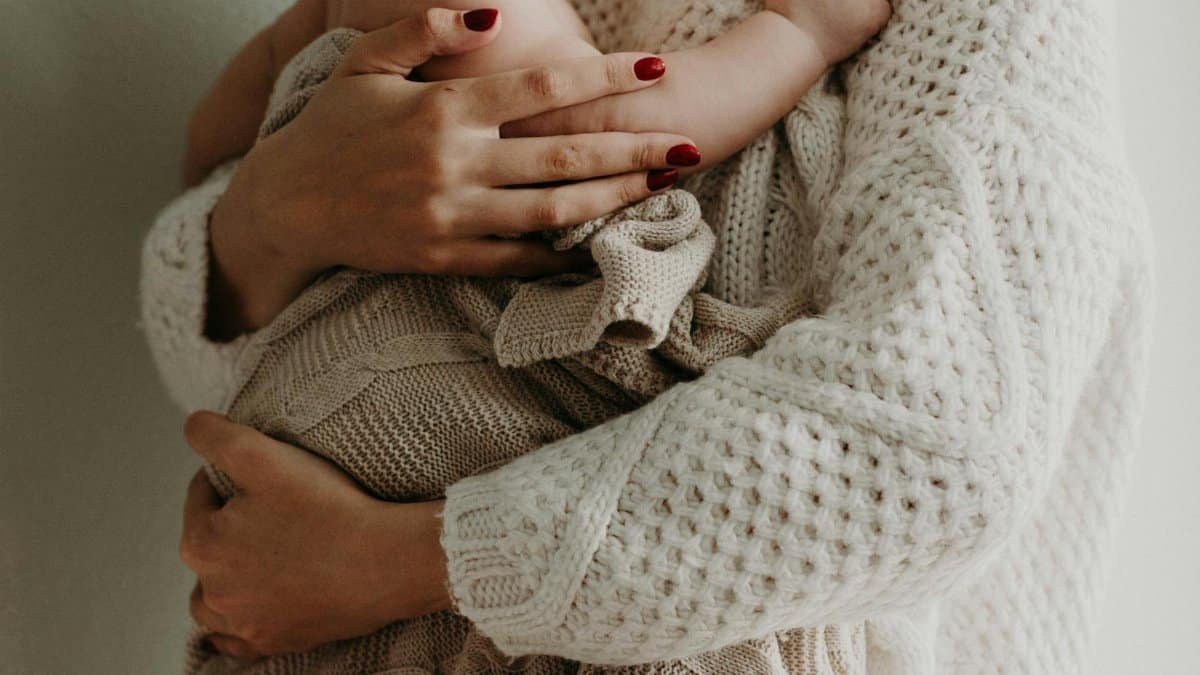 Close-up of a mother holding her baby in warm knitwear, conveying love and togetherness.