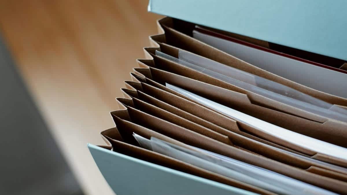 High angle of opened briefcase for documents with papers accosted in order placed on wooden table