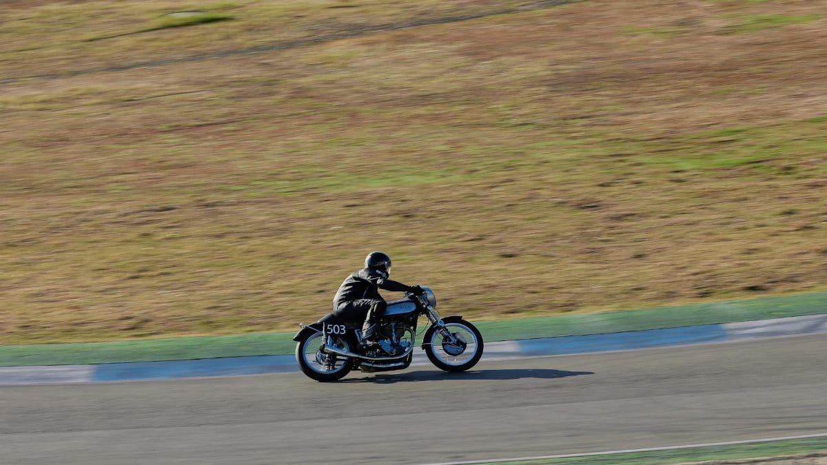 Motorcyclist on vintage bike racing on track during the day.