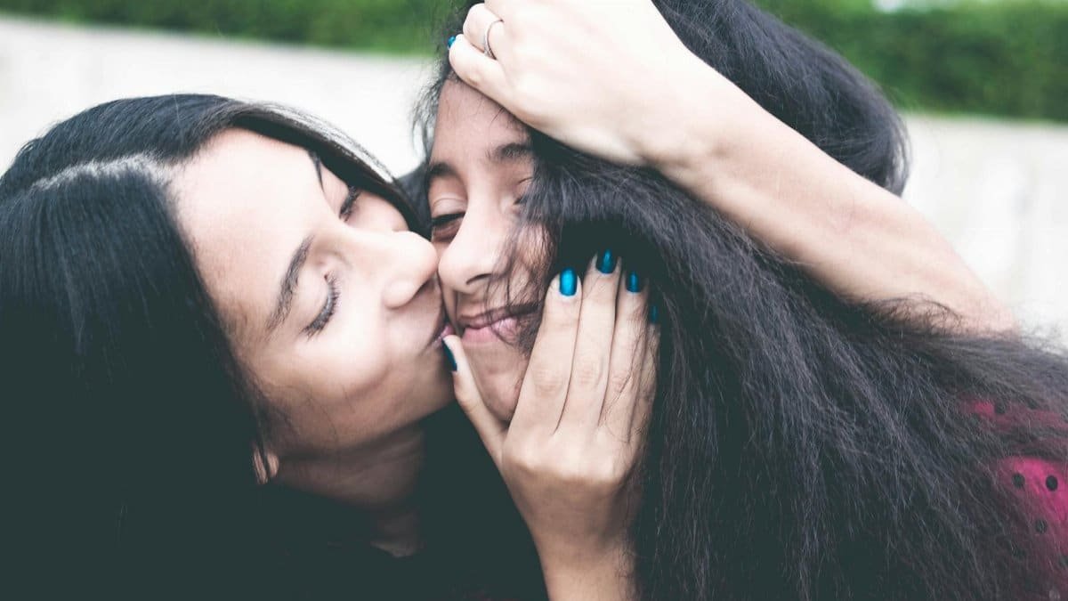 A mother and daughter share a loving embrace outdoors, capturing a tender family moment full of warmth and happiness.