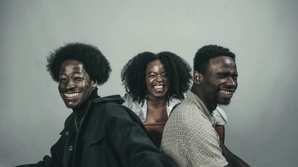 A trio of friends smiling and enjoying a great time indoors. Their happiness is contagious.