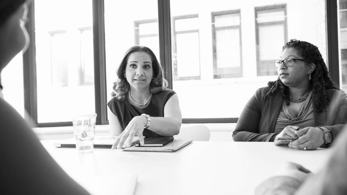 A diverse group of women engaging in a professional business meeting in a modern office setting.