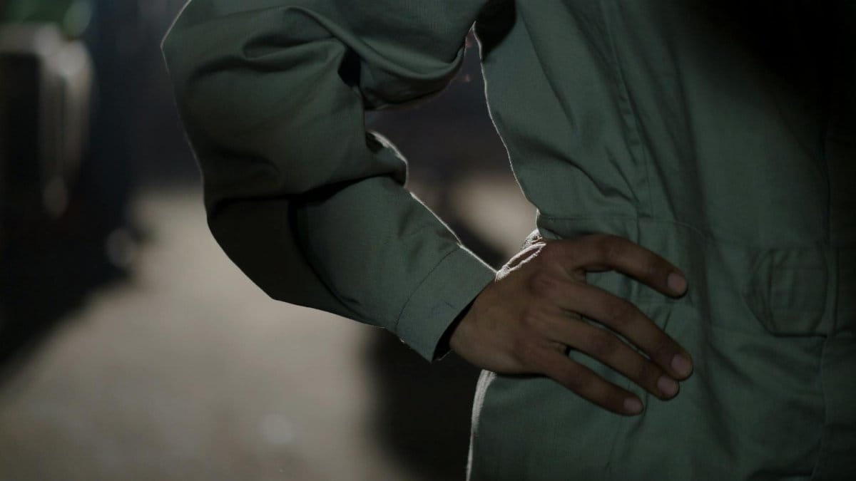 Close-up of a worker in a boiler suit posing with a hand on waist, creating a professional and industrial vibe.