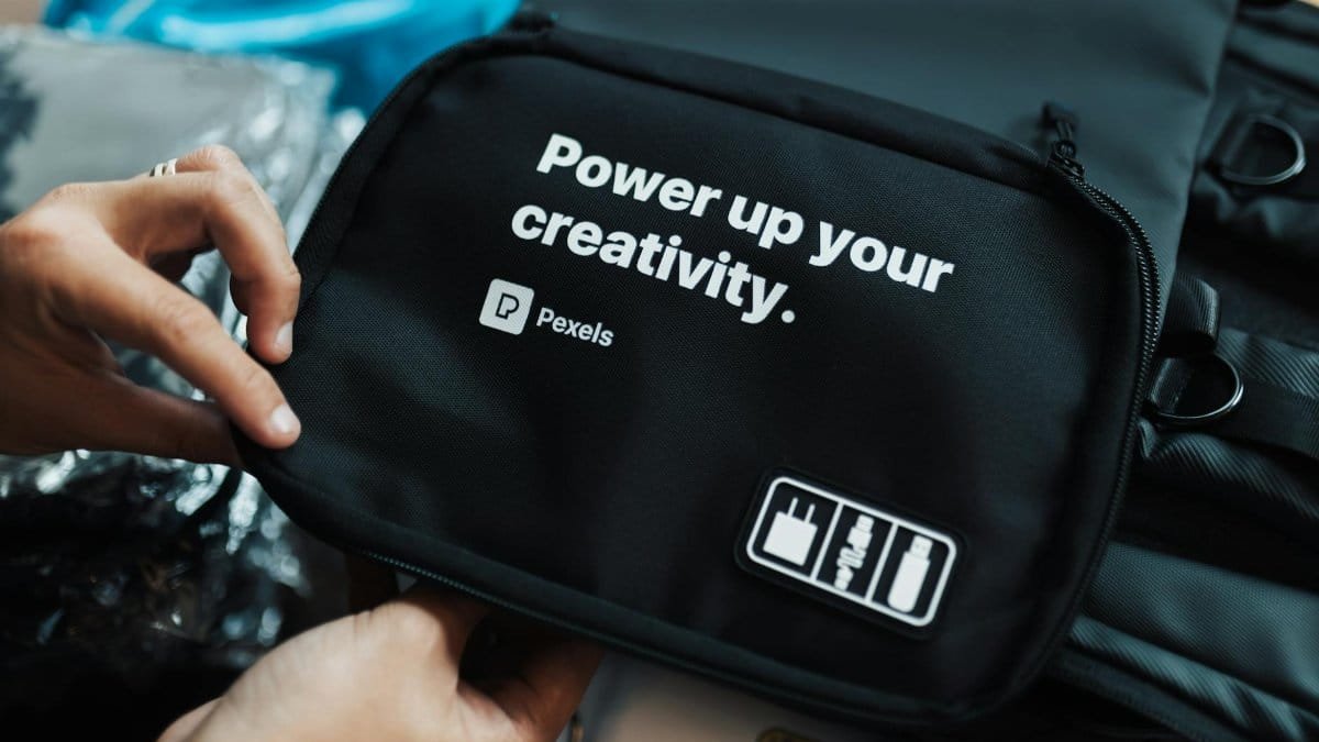 Hands holding a black bag with a creative slogan printed on it.