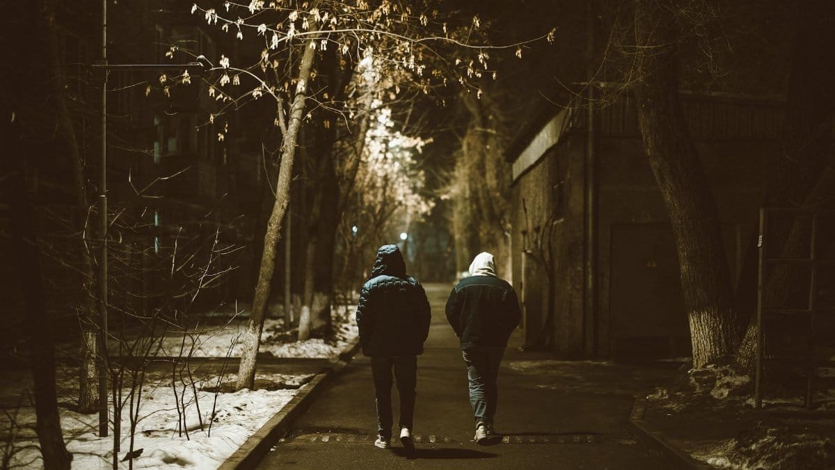 Two people walking at night on a snowy street in Almaty, Kazakhstan.