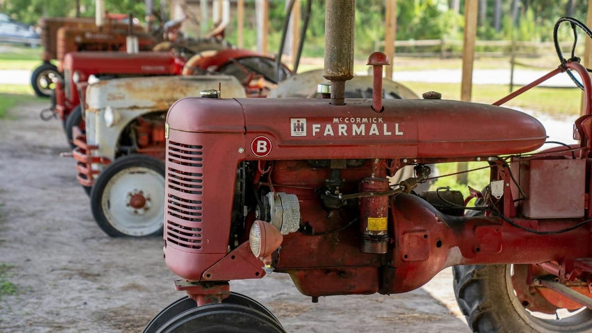 A collection of vintage McCormick Farmall tractors parked under a shelter on a North Carolina farm.