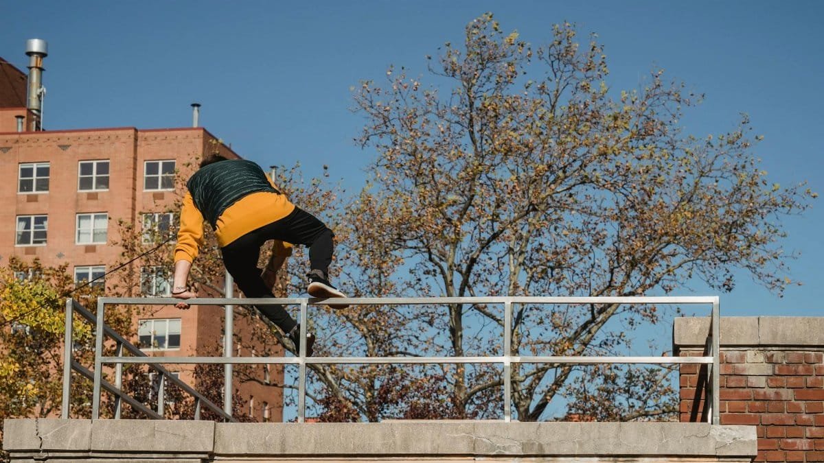 Back view of faceless male in activewear performing trick while practicing on height