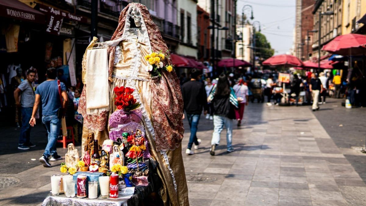 A vibrant Day of the Dead altar with colorful offerings in bustling Mexico City street.