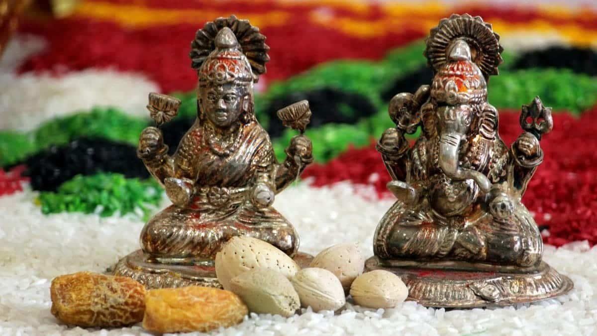 Metallic statues of Lakshmi and Ganesha surrounded by nuts and grains, symbolizing prosperity.