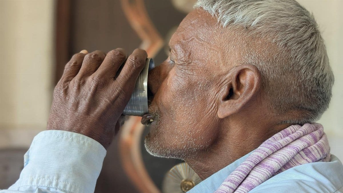 Close-up of an elderly man drinking from a metal cup, showcasing everyday life.