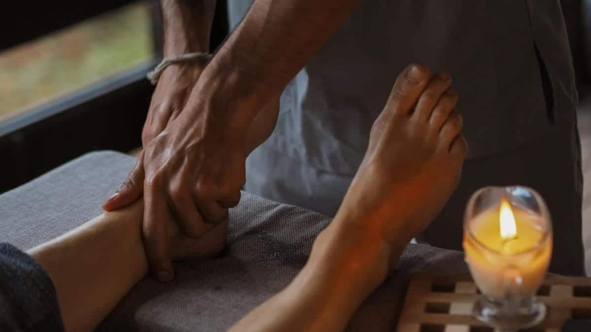 Close-up of a soothing foot massage in a dimly lit spa setting with a candle.