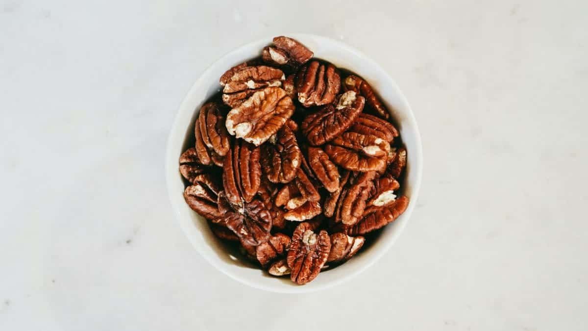 Top view of a bowl filled with healthy pecan nuts on a light surface, ideal for nutrition themes.