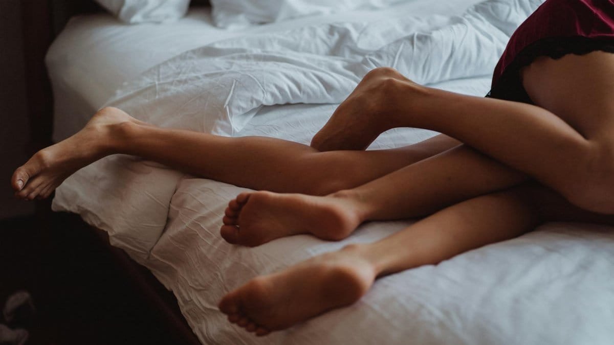 A close-up of intertwined legs illustrating intimacy and relaxation on a bed.