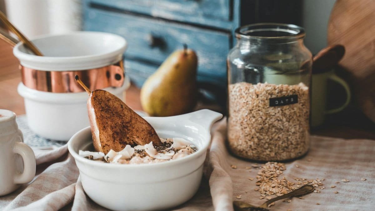 A cozy breakfast scene with a bowl of oats, sliced pear, and a rustic kitchen setting.