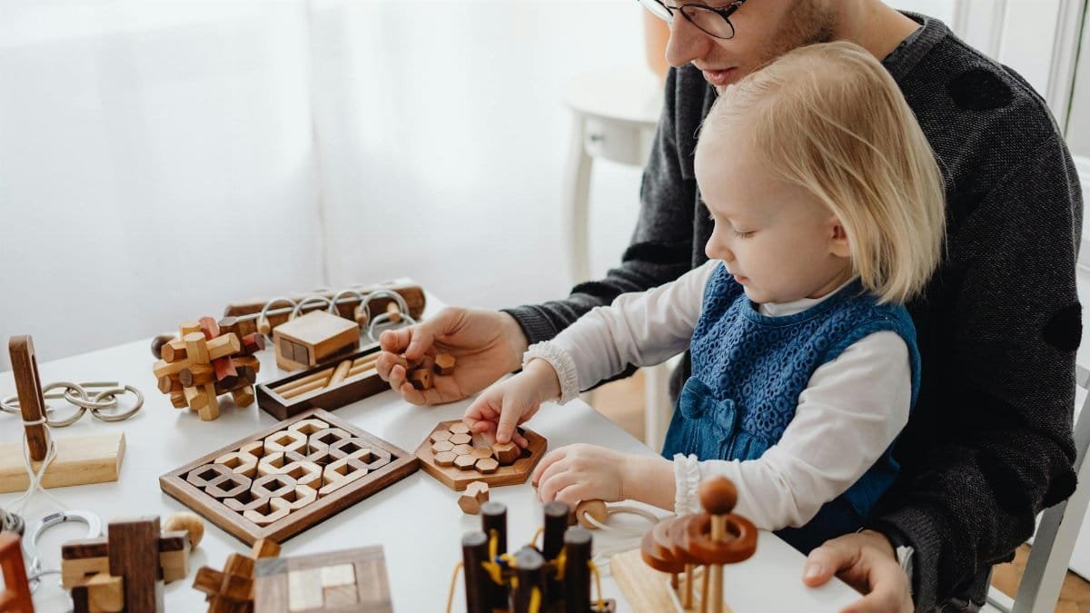 A father and child enjoying wooden puzzles together at a table indoors, fostering creativity and learning.