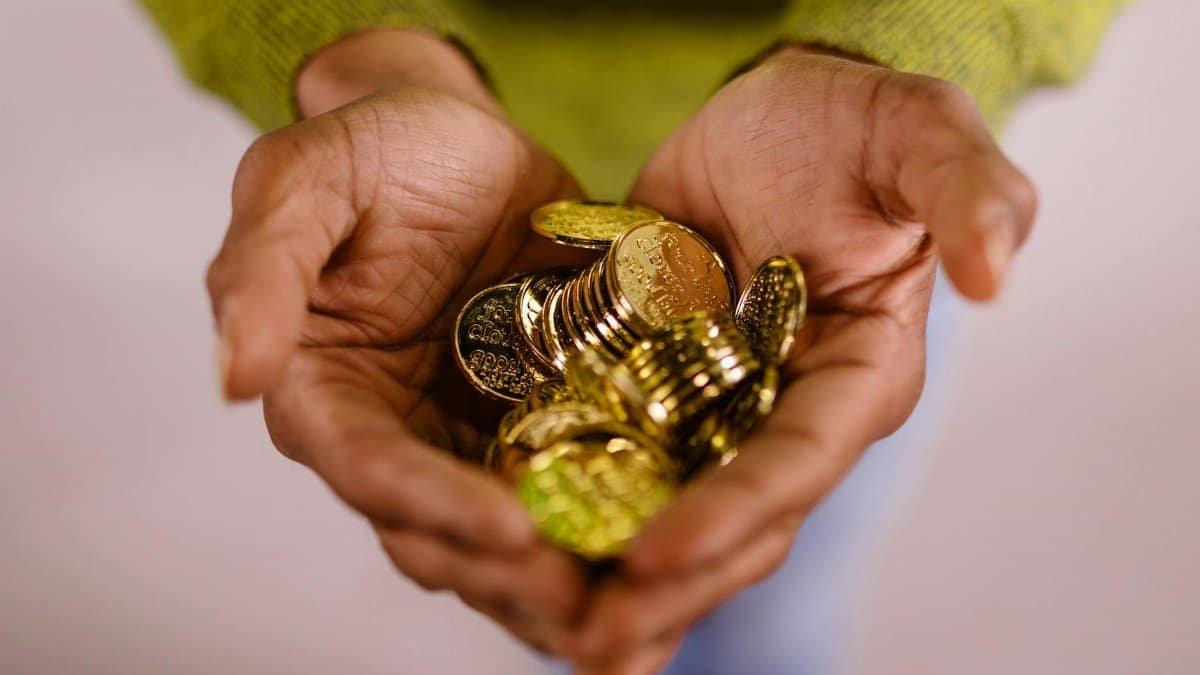 Close-up of hands cupping shiny gold coins, symbolizing wealth and prosperity.
